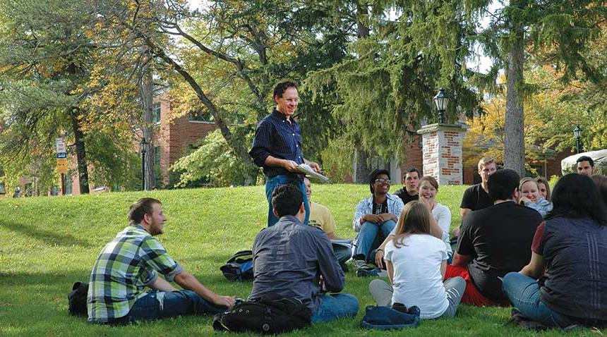 teacher and students having a class outside on the grass